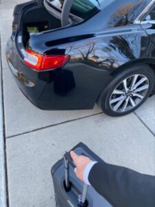 Chauffeur loading luggage in black car